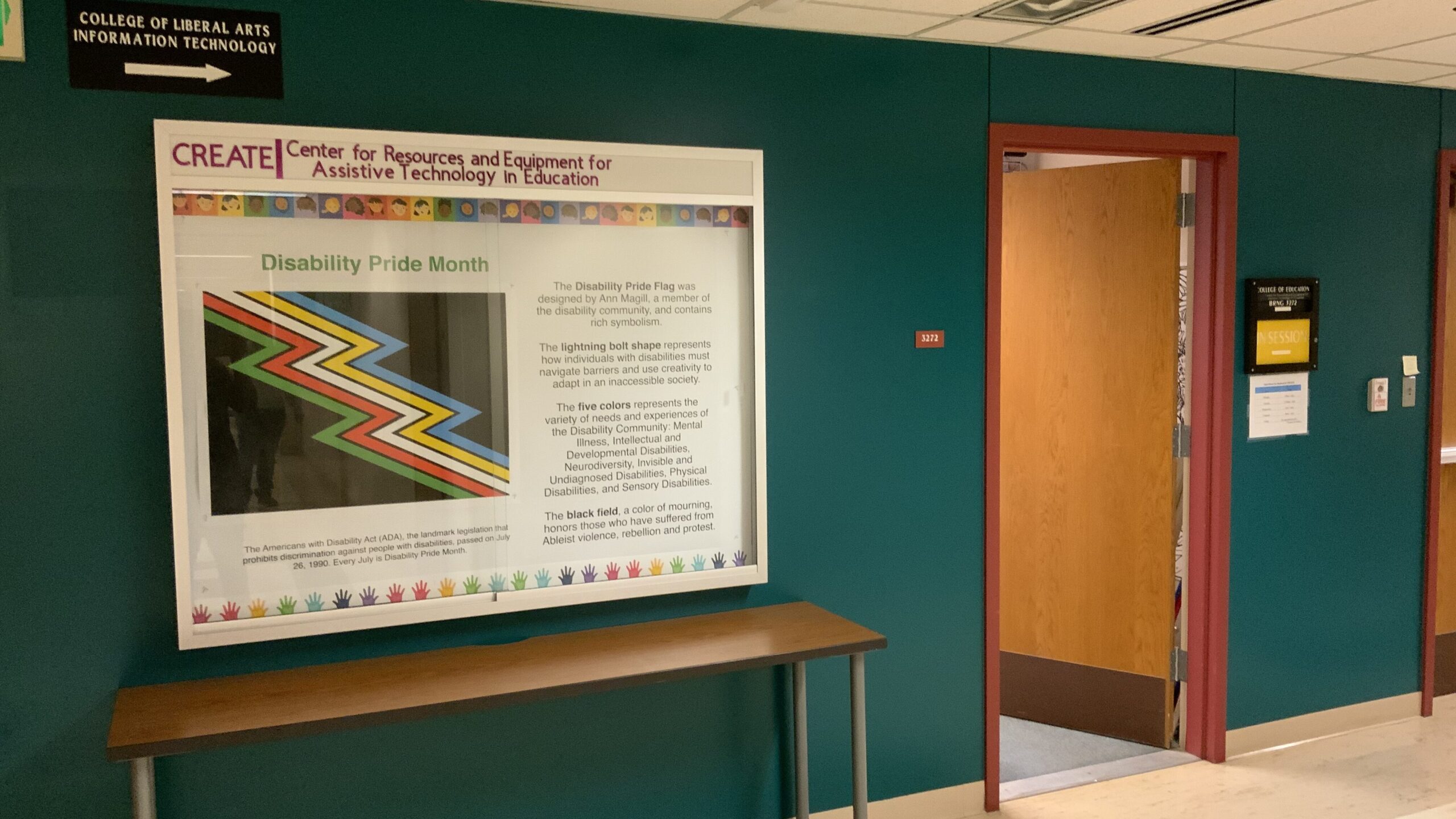 Hallway view of CREATE's room, featuring a large poster titled Disability Pride Month.